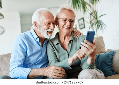 Portrait of an elderly senior couple using a mobile phone at home - Powered by Shutterstock