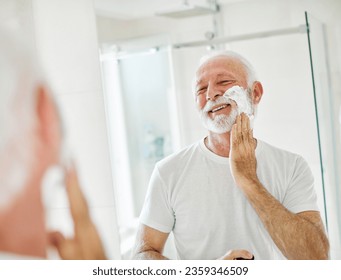 Portrait of an elderly senior man, face, shaving cream on beard, skincare treatment in front of mirror in bathroom. Healthy active mature man morning shave routine, vitality, hygiene, domestic life   - Powered by Shutterstock