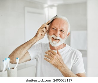 Portrait of an elderly senior man grooming and combing his beard and hair in front of  mirror in bathroom - Powered by Shutterstock