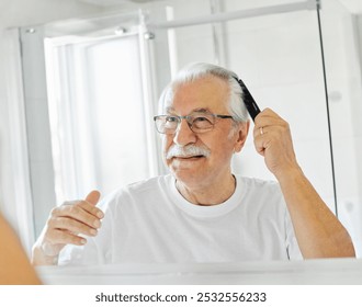 Portrait of an elderly senior man grooming and combing his hair in front of  mirror in bathroom - Powered by Shutterstock