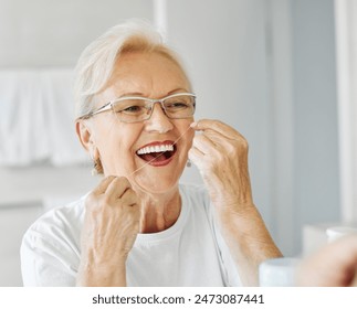 Portrait of an elderly senior woman is cleaning brushing his teeth using dental floss in front of mirror in bathroom. Dental hygiene, vitality and beauty concepts - Powered by Shutterstock
