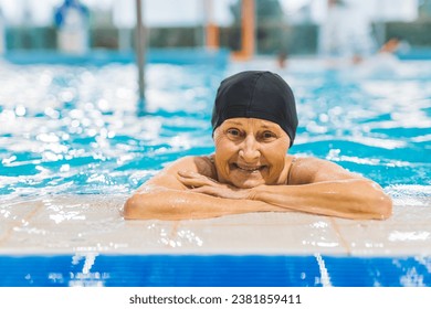 Portrait of elderly woman against the edge of a swimming pool and looking at camera. Fit and active senior woman enjoying retirement in the swimming pool. High quality photo - Powered by Shutterstock