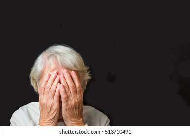 Portrait Of An Elderly Woman With Face Closed By Hands On Black