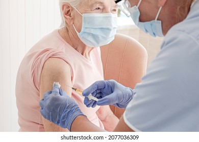 Portrait Of Elderly Woman At The Hospital Being Vaccinated By A Female Nurse. Senior Lady Wearing Face Mask Getting An Immunization Shot. Close Up, Copy Space, Background.