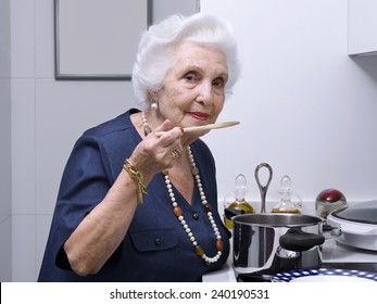 Portrait of an elderly woman in the kitchen, tasting the food - Powered by Shutterstock