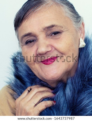 Portrait of an elderly woman. An old lady hipster with a fur collar. Elderly people, the concept of fashion. Fashionable hipster woman posing for the camera.