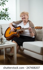 Portrait Of Elderly Woman Playing The Guitar