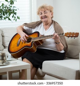 Portrait Of Elderly Woman Playing The Guitar