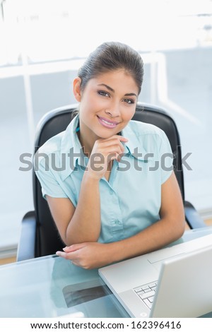 Portrait of an elegant businesswoman with laptop at desk in a bright office