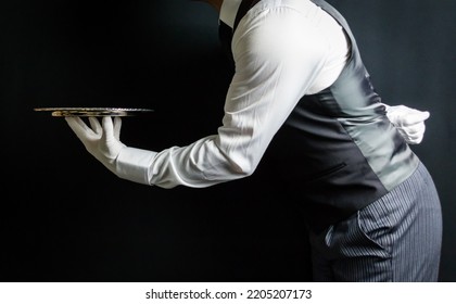 Portrait of Elegant Butler or Waiter In Waistcoat and White Gloves Holding Silver Serving Tray. At Your Service Concept. Professional Hospitality.