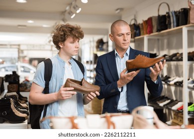 Portrait of elegant man and interested teenage boy choosing stylish dress shoes in shoe boutique. - Powered by Shutterstock