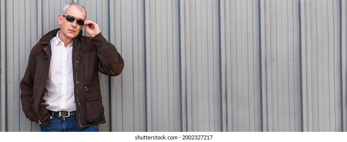 Portrait Of Elegant Mature Man In Sunglasses Leaning On City Blind