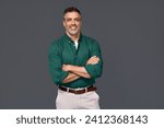 Portrait of elegant older business man, smiling middle aged mature businessman professional executive or lawyer wearing green shirt looking at camera standing arms crossed isolated on gray background.
