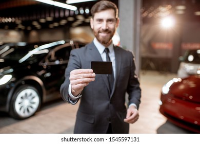 Portrait Of An Elegant Salesman With A Card Key, Selling Electric Vehicles At The Car Dealership