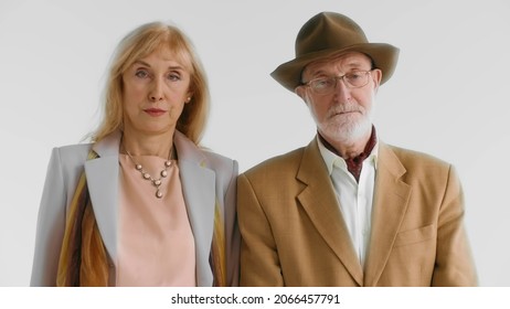 Portrait Of Elegant Senior Serious Couple Isolated On White Background. Medium Shot Of Attractive Aged Man And Woman Looking At Camera