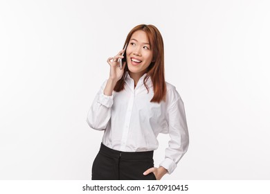 Portrait Of Elegant Successful Asian Businesswoman Calling Person, Holding Mobile Phone Near Ear And Smiling, Arrange Meeting Via Smartphone, Order Food Delivery To Office, White Background