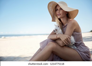 Portrait of an elegant woman relaxing on a beach with her beloved dog