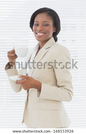 Portrait of an elegant young smiling businesswoman with a cup of tea in the office