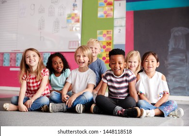 Portrait Of Elementary School Pupils Sitting On Floor In Classroom