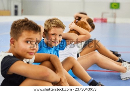 Portrait of elementary schoolboy doing exercise with friends during gym class