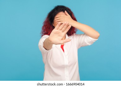 Portrait Of Embarrassed Woman Showing Stop Gesture, Covering Eyes With Hands So Not To Watch Forbidden Shameful Content, Pretending To Not See Problems. Indoor Studio Shot Isolated On Blue Background