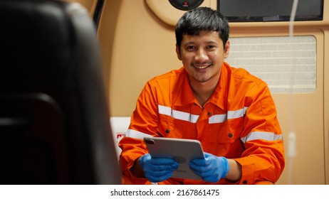 Portrait Of Emergency Medical Technician (EMT) Asian Man Or Paramedic Smiling And Looking At Camera While Sitting In Ambulance Car