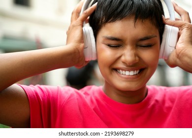 Portrait Of Emotional Beautiful Asian Woman With Eyes Closed Wearing Wireless Headphones Listening Music On The Street 