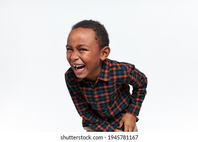 Portrait Of Emotional Overjoyed Afro American Little Boy In Plaid Shirt Bending And Opening Mouth Widely, Showing Milk Teeth, Bursting Into Loud Laugh. Cute Black Child Laughing At Joke Or Prank
