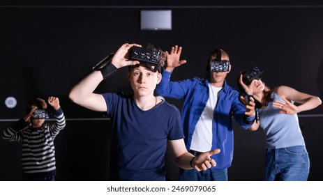 Portrait of emotional surprised teenage boy wearing VR headset playing virtual reality games with his parents and little brother - Powered by Shutterstock