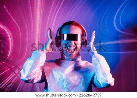 Portrait of emotionally shouting woman in futuristic sunglasses and headphones in pink and blue neon light. Music lover. Silent disco. Woman on background of music vibes background. Futuristic Party