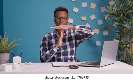Portrait of employee showing timeout gesture and looking at camera, expressing wish to take break and pause from work. Overworked man asking for half time, to control limits finish.