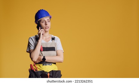 Portrait Of Empowered Handywoman Answering Phone Call To Work On Construction Building Repair. Strong Person Talking On Smartphone Line And Do Renovation Project With Tools In Studio.