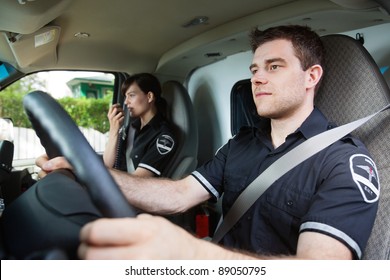Portrait Of EMS Worker Driving Ambulance While Team Member Talks With Dispatcher
