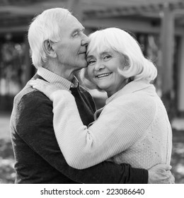 Portrait Of Endless Love. Black And White Portrait Of Happy Senior Couple Bonding To Each Other And Smiling While Standing Outdoors And In Front Of Their House 