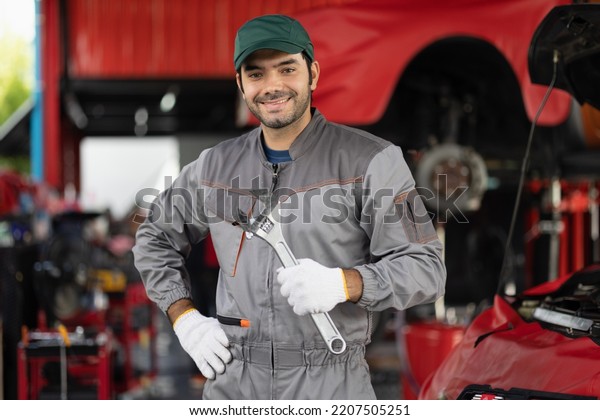 Portrait engine maintenance car mechanic with\
holding wrench self-confident with looking at camera. diagnostic\
and repairing vehicle at garage automotive, Car care check and\
fixed services\
concept.