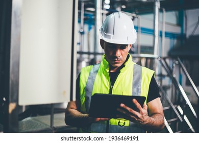 Portrait Of Engineer Foreman Writing On Digital Tablet And Checking In Industrial Factory. Worker In Safety Uniform Working At Construction Site. Heavy Machine Technology Industry Concept. Copy Space