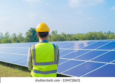 Portrait Of Engineer Man Or Worker, People, With Solar Panels Or Solar Cells On The Roof In Farm. Power Plant With Green Field, Renewable Energy Source In Thailand. Eco Technology For Electric Power.