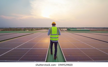 Portrait Of Engineer Man Or Worker, People, Working On Solar Panels Or Solar Cells On The Roof In Factory Industry. Power Plant, Renewable Energy Source. Eco Technology For Electric Power. Maintenance