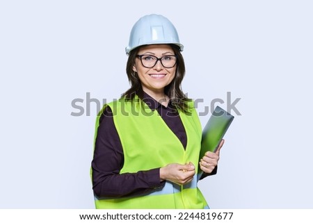 Portrait of engineer manager woman in helmet vest holding laptop