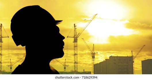 portrait of engineer silhouette wear hard hat, helmet at construction site with crane background and sunset. Silhouette engineer wear a helmet at construction site with crane background and sun