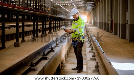Portrait engineer under inspection and checking construction process railway and checking work on railroad station .Engineer wearing safety uniform and safety helmet in work.