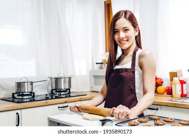 Portrait Of Enjoy Happy Asian Woman Having Fun Cooking With Baking Cookies And Cake Ingredients On Table In Kitchen