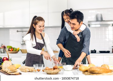 Portrait Of Enjoy Happy Love Asian Family Father And Mother With Little Asian Girl Daughter Child Having Fun Cooking Together With Baking Cookies And Cake Ingredients On Table In Kitchen