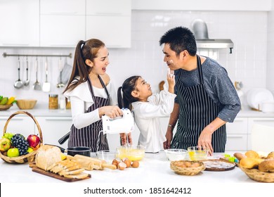 Portrait Of Enjoy Happy Love Asian Family Father And Mother With Little Asian Girl Daughter Child Having Fun Cooking Together With Baking Cookies And Cake Ingredients On Table In Kitchen