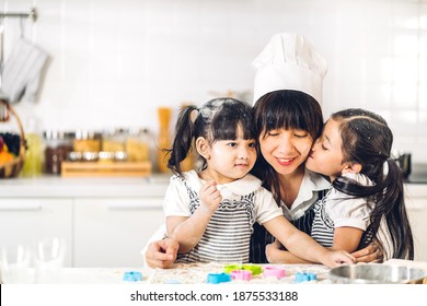 Portrait Of Enjoy Happy Love Asian Family Mother And Little Asian Girl Daughter Child Having Fun Cooking Together With Baking Cookies And Cake Ingredients On Table In Kitchen