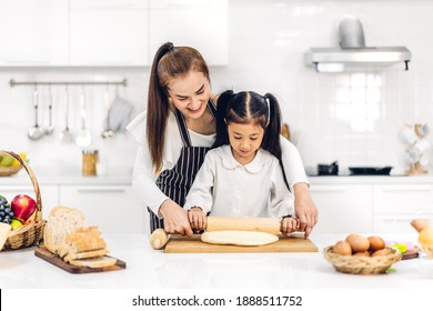 Portrait Of Enjoy Happy Love Asian Family Mother And Little Asian Girl Daughter Child Having Fun Cooking Together With Baking Cookies And Cake Ingredients On Table In Kitchen