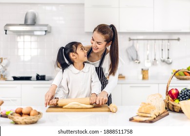 Portrait Of Enjoy Happy Love Asian Family Mother And Little Asian Girl Daughter Child Having Fun Cooking Together With Baking Cookies And Cake Ingredients On Table In Kitchen