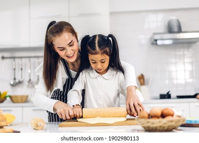 Portrait Of Enjoy Happy Love Asian Family Mother And Little Asian Girl Daughter Child Having Fun Cooking Together With Baking Cookies And Cake Ingredients On Table In Kitchen