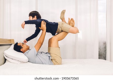 Portrait of enjoy happy love asian family father carrying little asian boy son smiling playing superhero and having fun moments good time on bed at home - Powered by Shutterstock