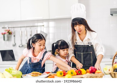 Portrait Of Enjoy Happy Love Asian Family Mother And Little Asian Girl Daughter Child Having Fun Cooking Together With Fresh Vegetable Salad And Sandwich Ingredients On Table In Kitchen